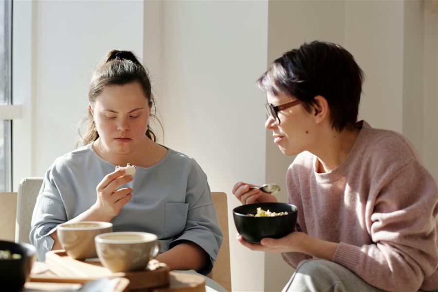 Support worker sharing a meal with an NDIS participant at home in Sydney