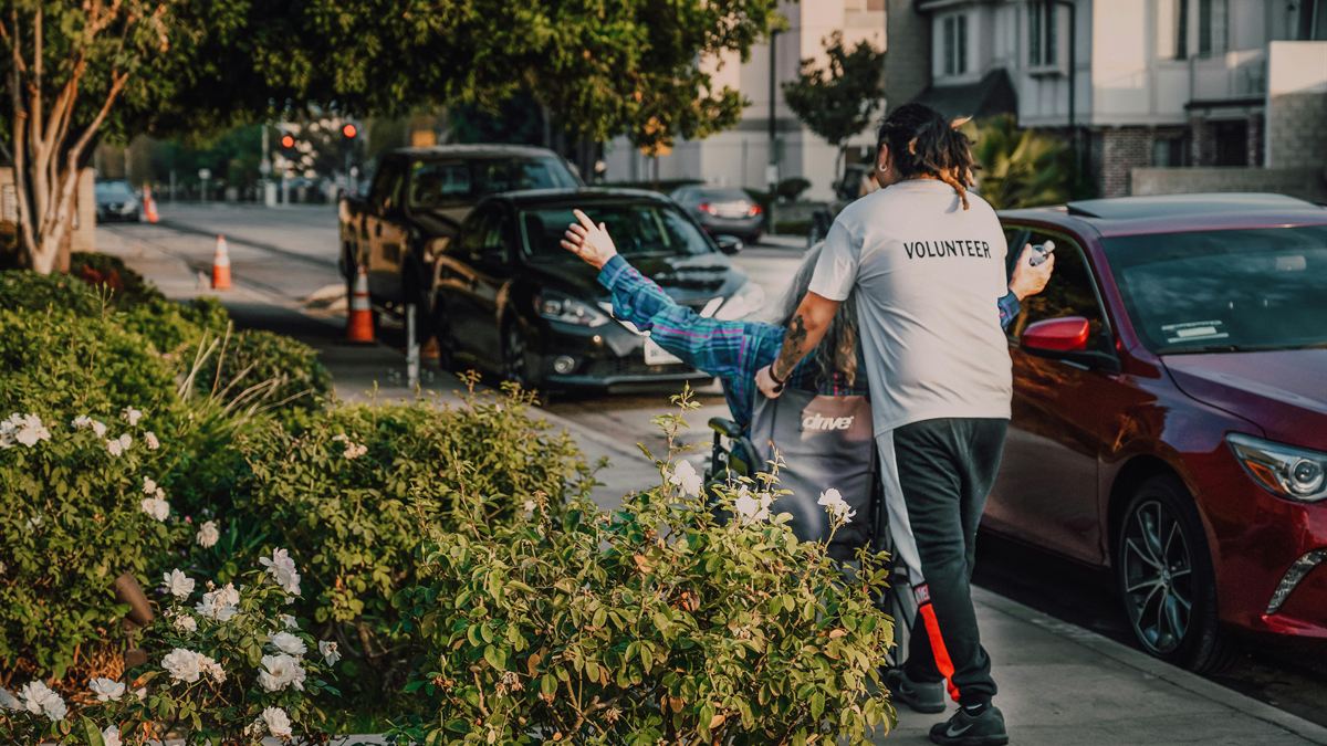 Support worker wheeling a participant to the car for a community outing
