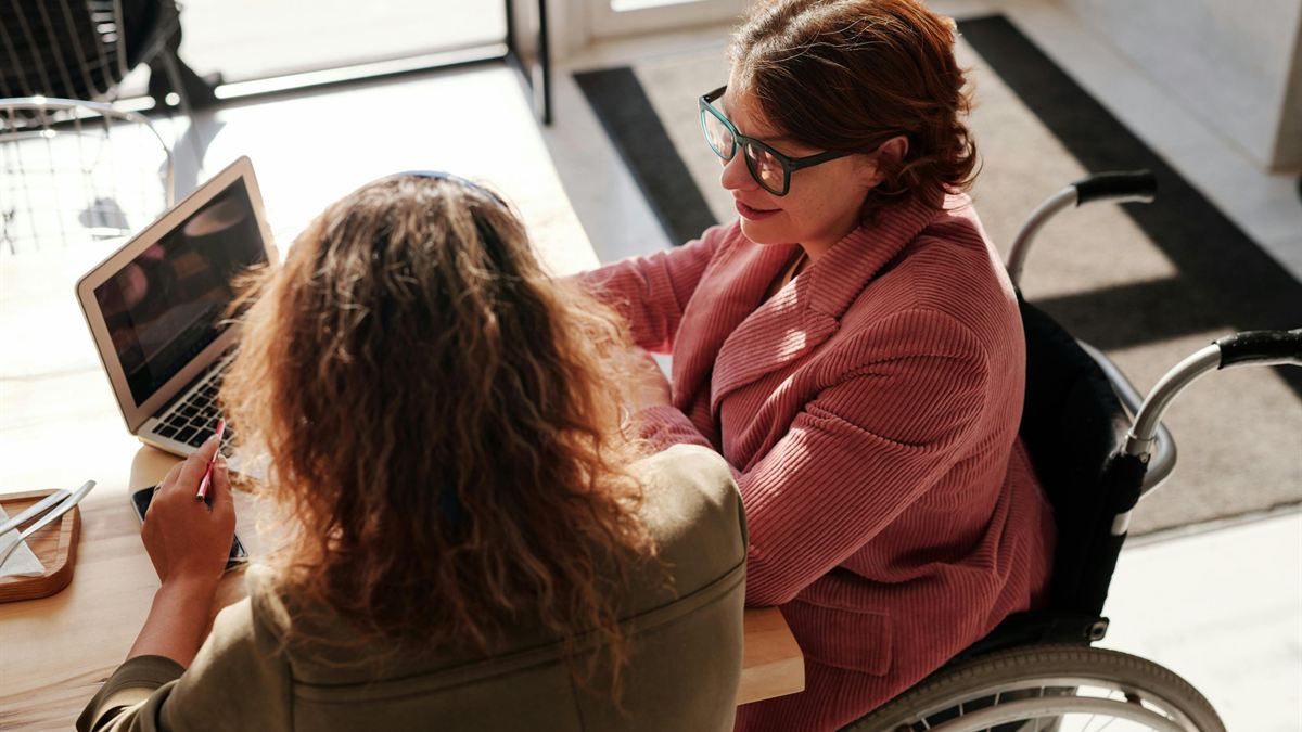 Support coordinator reviewing an NDIS plan with a participant on a laptop